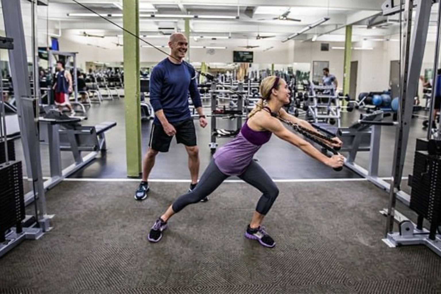 Man och kvinna tränar på gym med vikter, symboliserar aktivitet i idrottsförening.